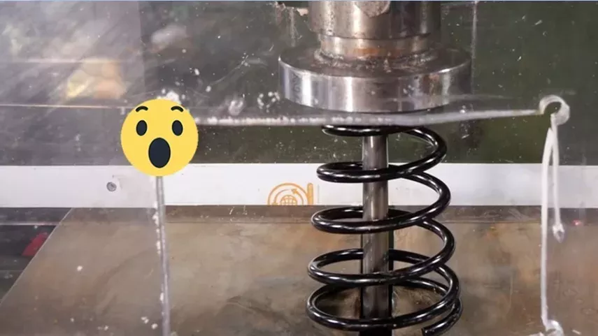 Eine Hydraulikpresse zerquetscht einen Stoßdämpfer