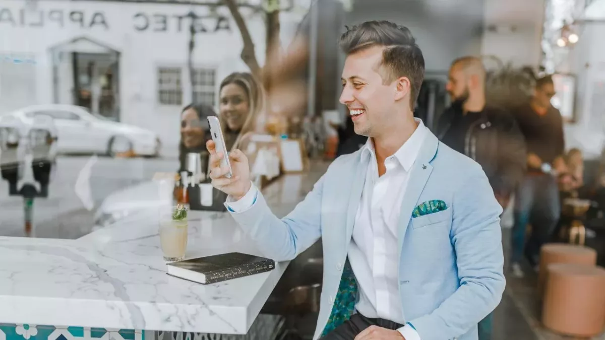 Ein Mann mit Smartphone sitzt in einer Gastronomie