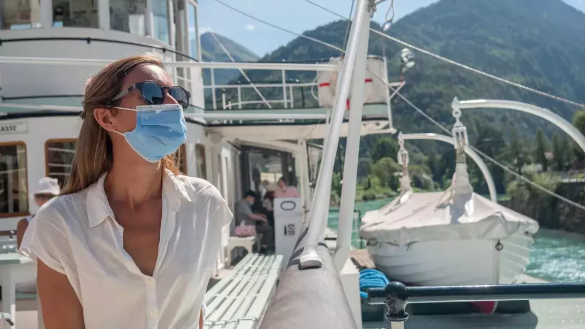 Eine Frau mit Mundnasenschutz steht auf einem Kreuzfahrtschiff