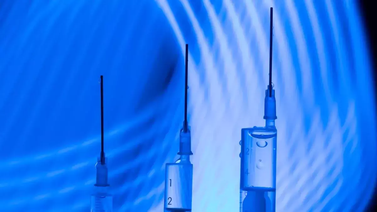 Vaccine research concept: three syringes in a modern laboratory context with curved blue lines