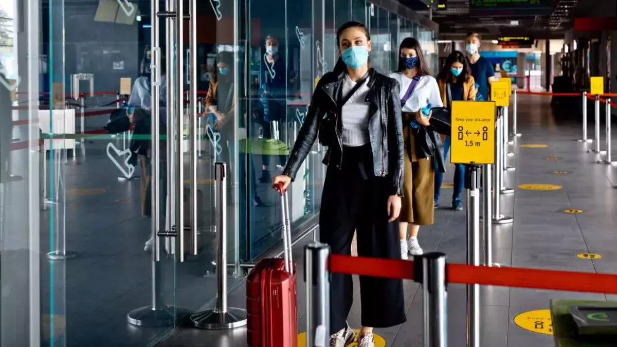 Passagiere mit N95 Gesichtsmaske warten in der Schlange eines Flughafenterminals