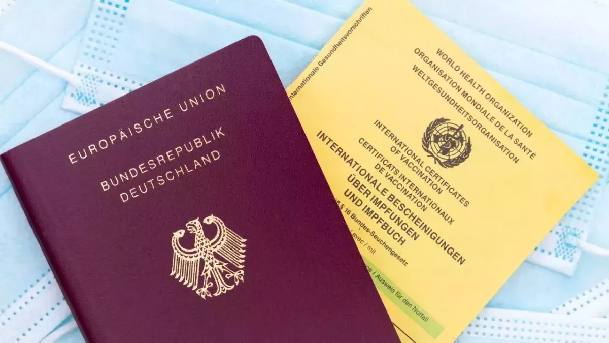 Ein deutscher Reisepass und eine  deutsche Impfbescheinigung liegen auf einem Mund-Nasen-Schutz