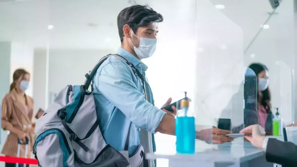 Ein Mann mit Maske bei einer Passkontrolle am Flughafen
