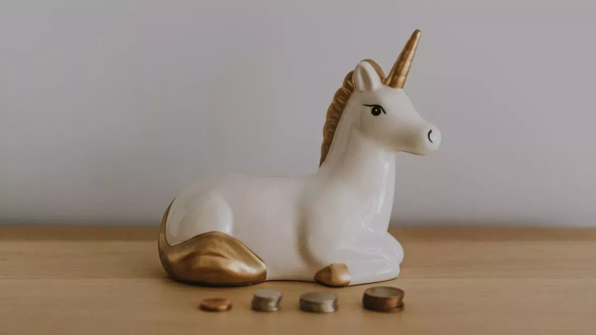 Eine Einhorn-Spardose steht umgeben von Münzen auf einem Tisch