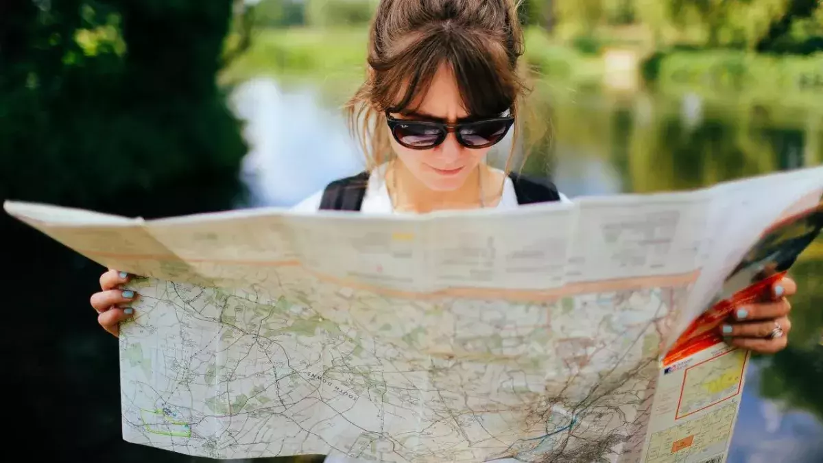 Eine Frau mit Sonnenbrille schaut in eine Landkarte