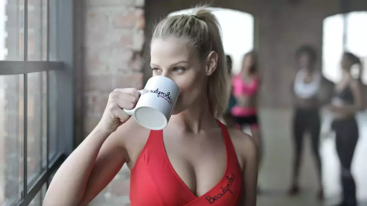 Frau in rotem Sportoberteil trinkt einen Kaffee