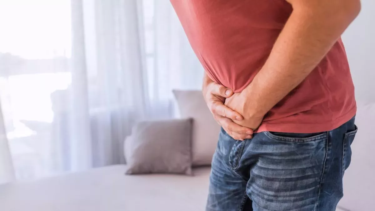 Mann krümmt sich und presst Hände an den Bauch