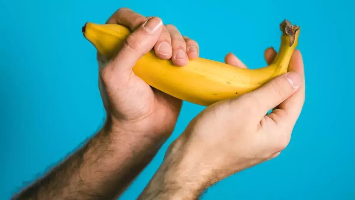 Zwei Hände halten eine Banane mit Kondom