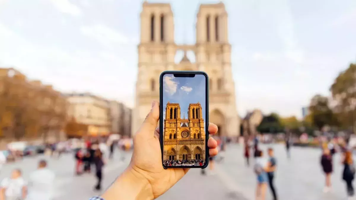Tourist taking picture of Notre Dame cathedral with smart phone, personal perspective view