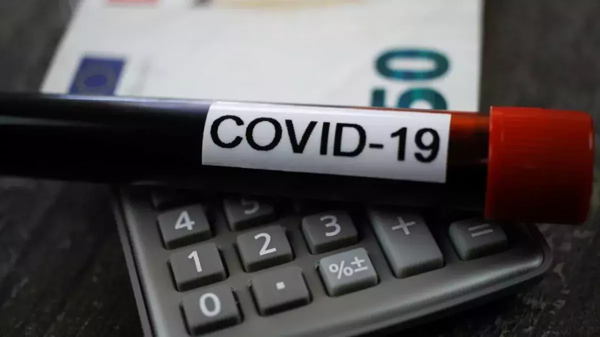 Berechnung des wirtschaftlichen Schadenskonzepts: covid-19 Blutprobenröhre auf Rechner, verschwommener 50-Euro-Scheinhintergrund