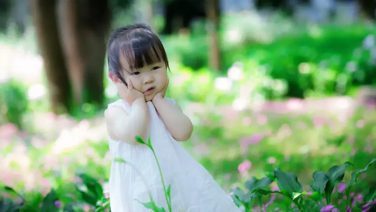 Ein kleines Mädchen in weißem Kleid auf einer Wiese in China
