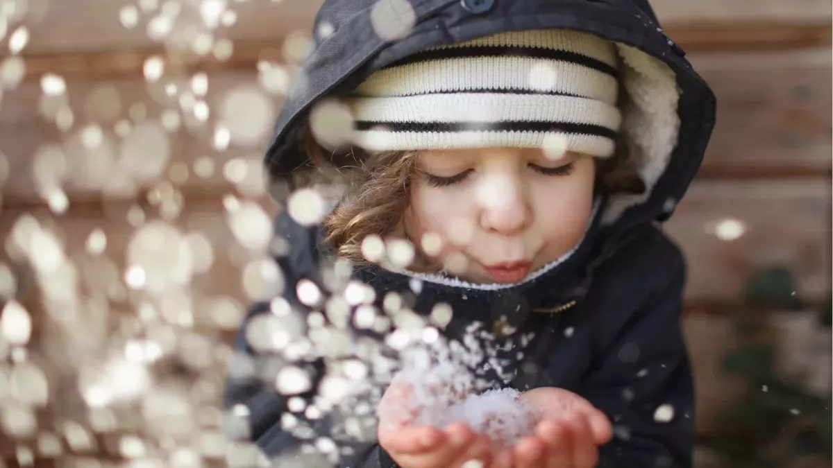 Kind pustet Schnee