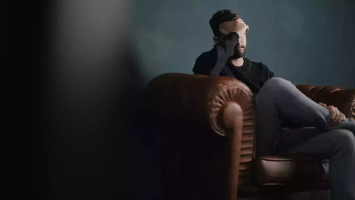 Mann hält Kopf auf Couch