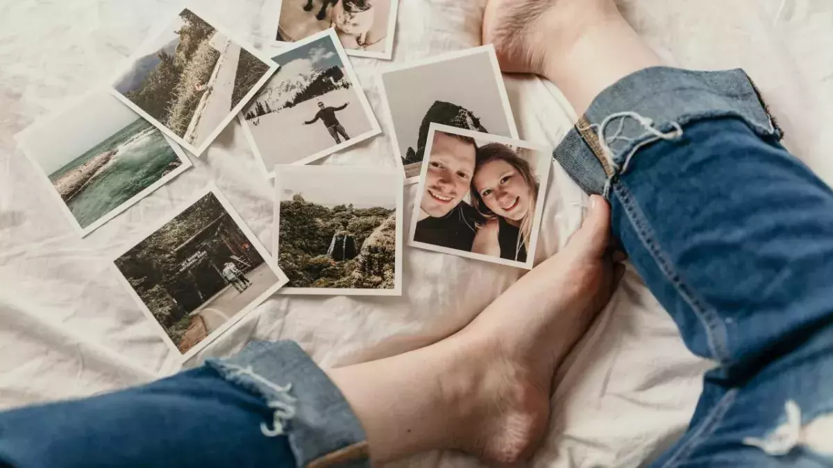 Polaroids liegen verstreut vor den Beinen einer Person auf einem Bett