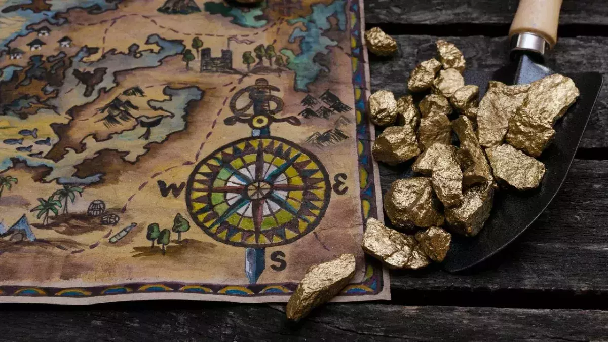 Treasure map and shovel full of gold nuggets ore on wooden table