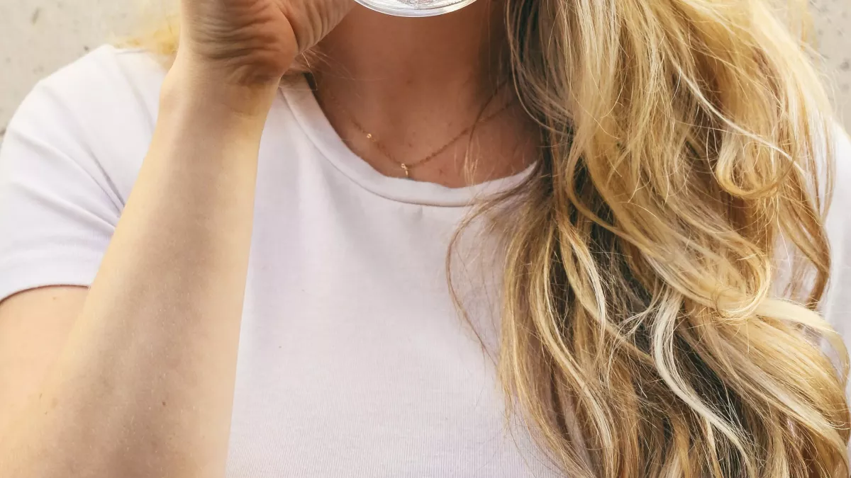 woman in white crew neck shirt drinking water