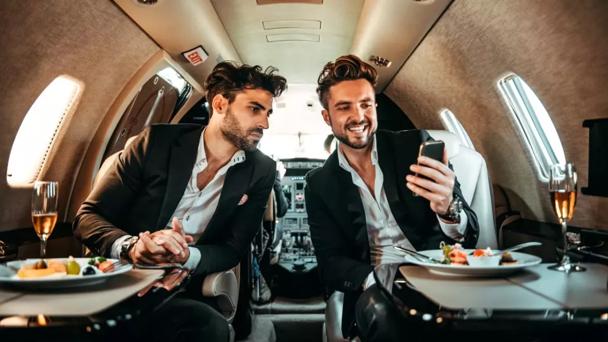 Zwei Manager benutzen ein Handy an Bord eines privaten Flugzeugs