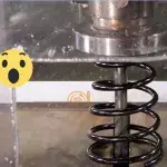 Eine Hydraulikpresse zerquetscht einen Stoßdämpfer
