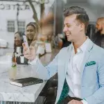 Ein Mann mit Smartphone sitzt in einer Gastronomie
