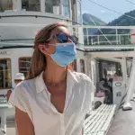 Eine Frau mit Mundnasenschutz steht auf einem Kreuzfahrtschiff