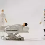Figuren eines Intensivpatienten und zweier Mediziner