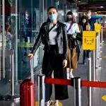Passagiere mit N95 Gesichtsmaske warten in der Schlange eines Flughafenterminals