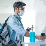 Ein Mann mit Maske bei einer Passkontrolle am Flughafen