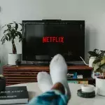 Ein Paar Beine mit Socken vor einem TV mit Netflix-Logo