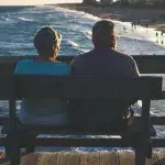 Ein Paar sitzt auf einer Bank am Meer