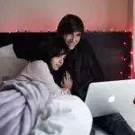 Ein Paar streamt auf einem Laptop im Bett
