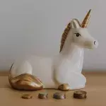 Eine Einhorn-Spardose steht umgeben von Münzen auf einem Tisch
