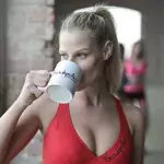 Frau in rotem Sportoberteil trinkt einen Kaffee
