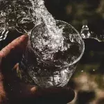Hand mit einem Glas Wasser