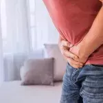 Mann krümmt sich und presst Hände an den Bauch