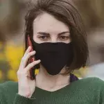 A woman talking on the phone with coronavirus mask