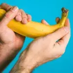 Zwei Hände halten eine Banane mit Kondom