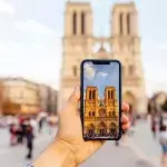 Tourist taking picture of Notre Dame cathedral with smart phone, personal perspective view