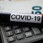 Berechnung des wirtschaftlichen Schadenskonzepts: covid-19 Blutprobenröhre auf Rechner, verschwommener 50-Euro-Scheinhintergrund