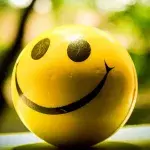 Ein gelber Ball mit Smiley-Gesicht vor grünem Hintergrund 