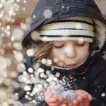 Kind pustet Schnee