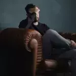 Mann hält Kopf auf Couch