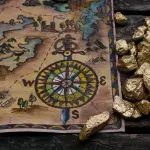 Treasure map and shovel full of gold nuggets ore on wooden table