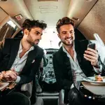 Zwei Manager benutzen ein Handy an Bord eines privaten Flugzeugs