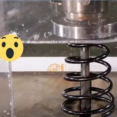 Eine Hydraulikpresse zerquetscht einen Stoßdämpfer