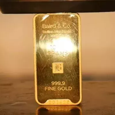 Ein Mann zerquetscht einen Goldbarren mit einer hydraulischen Presse