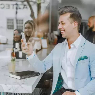 Ein Mann mit Smartphone sitzt in einer Gastronomie