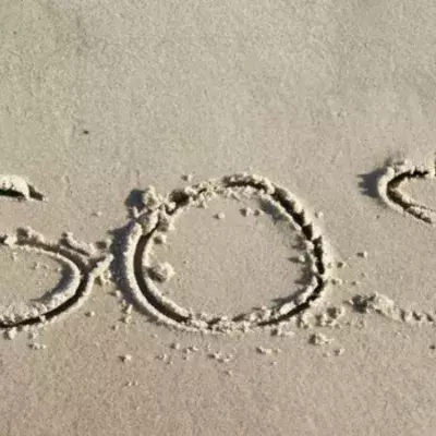 Gestrandet auf einer einsamen Insel rettet ihnen ein SOS im Sand das Leben