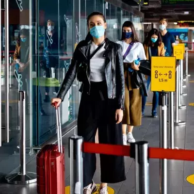 Passagiere mit N95 Gesichtsmaske warten in der Schlange eines Flughafenterminals