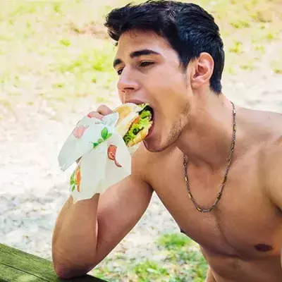 Ein Mann beißt genussvoll in einen fettigen Burger