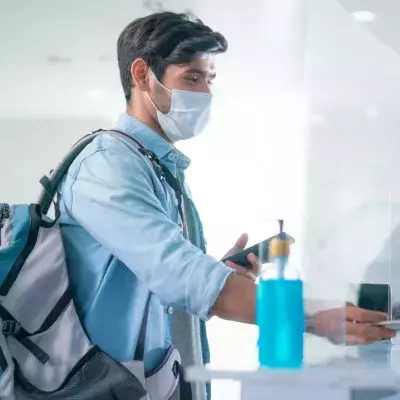 Ein Mann mit Maske bei einer Passkontrolle am Flughafen